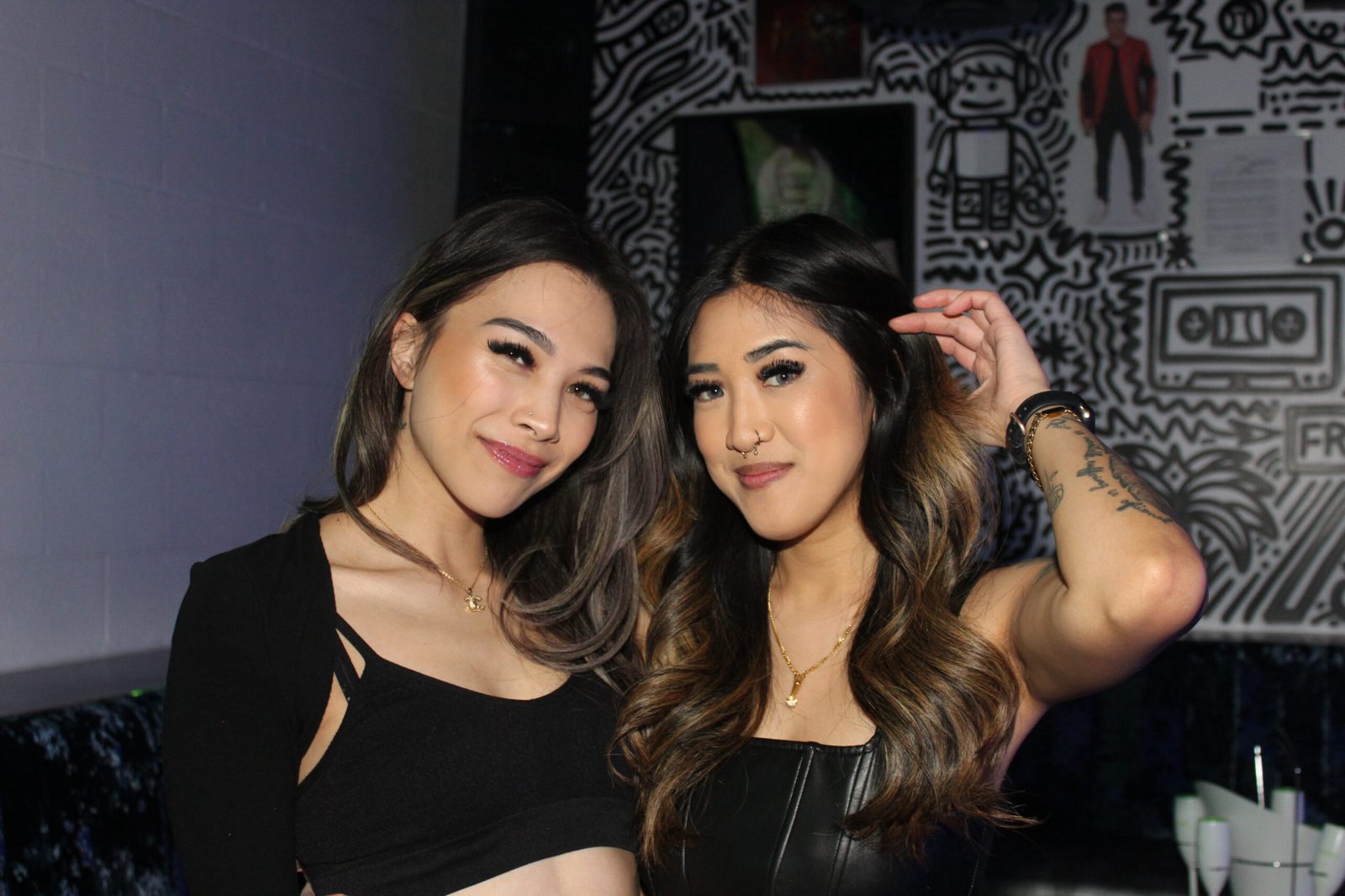 Two guests taking a photo in front of Audio Bar's mural wall
